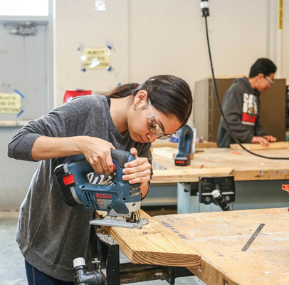 ACC Early College High School Student learning how to use a power tool in a workshop classroom.