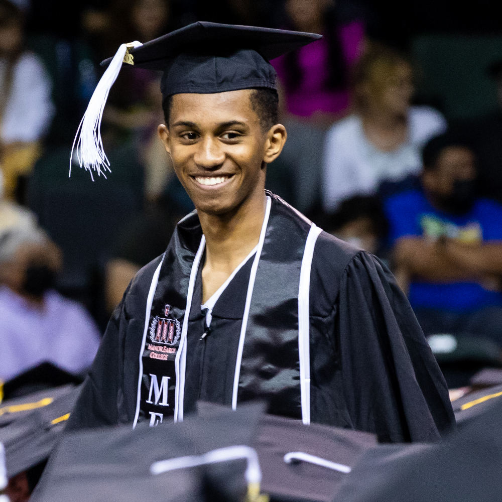 ACC Early College High School graduate at commencement walking down the aisle after receiving his diploma.